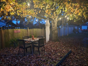 Eine Terrasse mit Tisch und Stühlen, umgeben von einem Holzzaun und einem Baum.