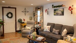 Una sala de estar con sofá, sillón y una mesa de centro con libros y un jarrón.