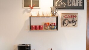 Una kitchenette con cafetera, tazas, hervidor y un letrero que indica que solo se aceptan pagos en efectivo.