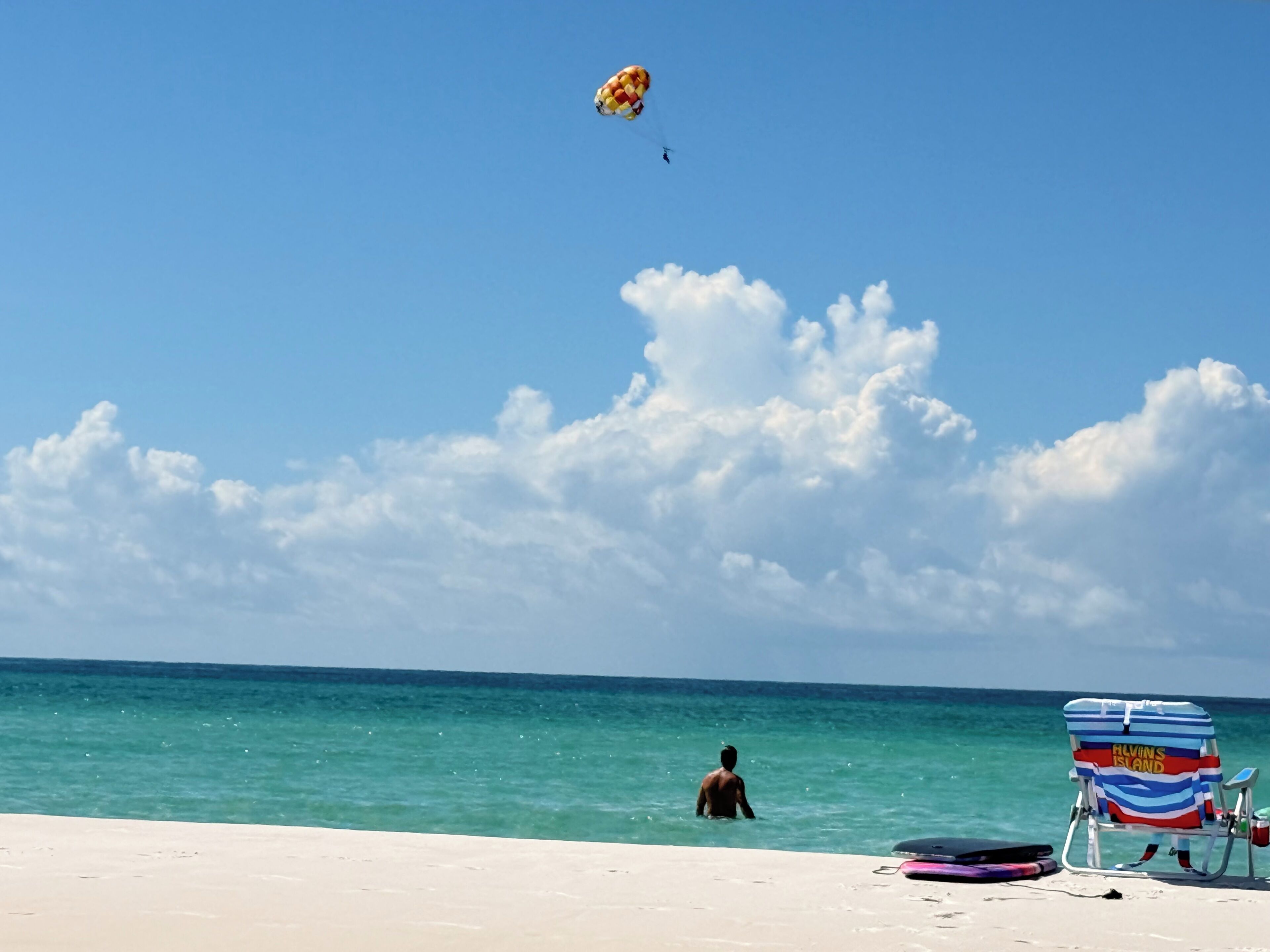 A beach scene with a clear sky, a person swimming, and a beach chair labeled 'Alvin's Island'.