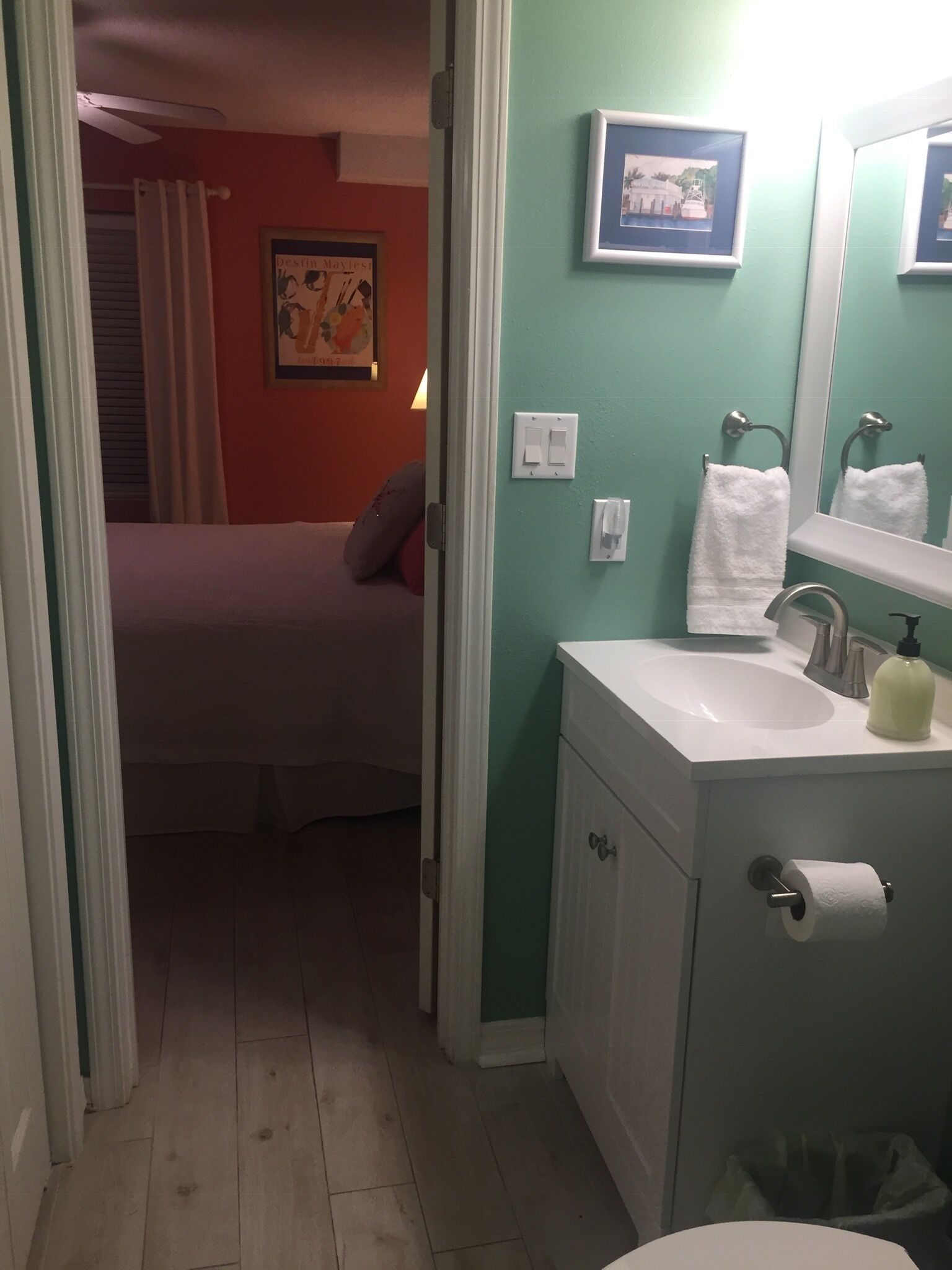 Une chambre à coucher avec un lit, une salle de bain avec un lavabo, un miroir et un porte-serviettes.