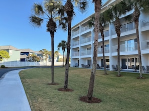 A multi-story hotel with balconies, palm trees, and outdoor seating.