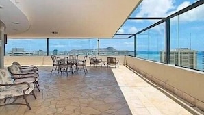 Een ruim balkon met stenen vloer en uitzicht op de stad en de oceaan.
