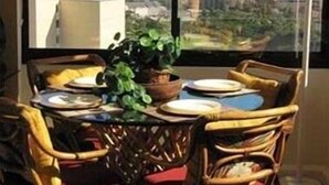 Een eetruimte met een tafel gedekt voor vier personen, met uitzicht op een stadslandschap en bergen in de verte.