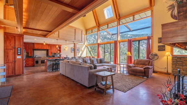A spacious living area with a large sofa, a fireplace, and a view of a mountainous landscape through large windows. - Carson View, amazing views of Carson Peak and Gull Lake, walk to Gull Lake & town (June Lake)