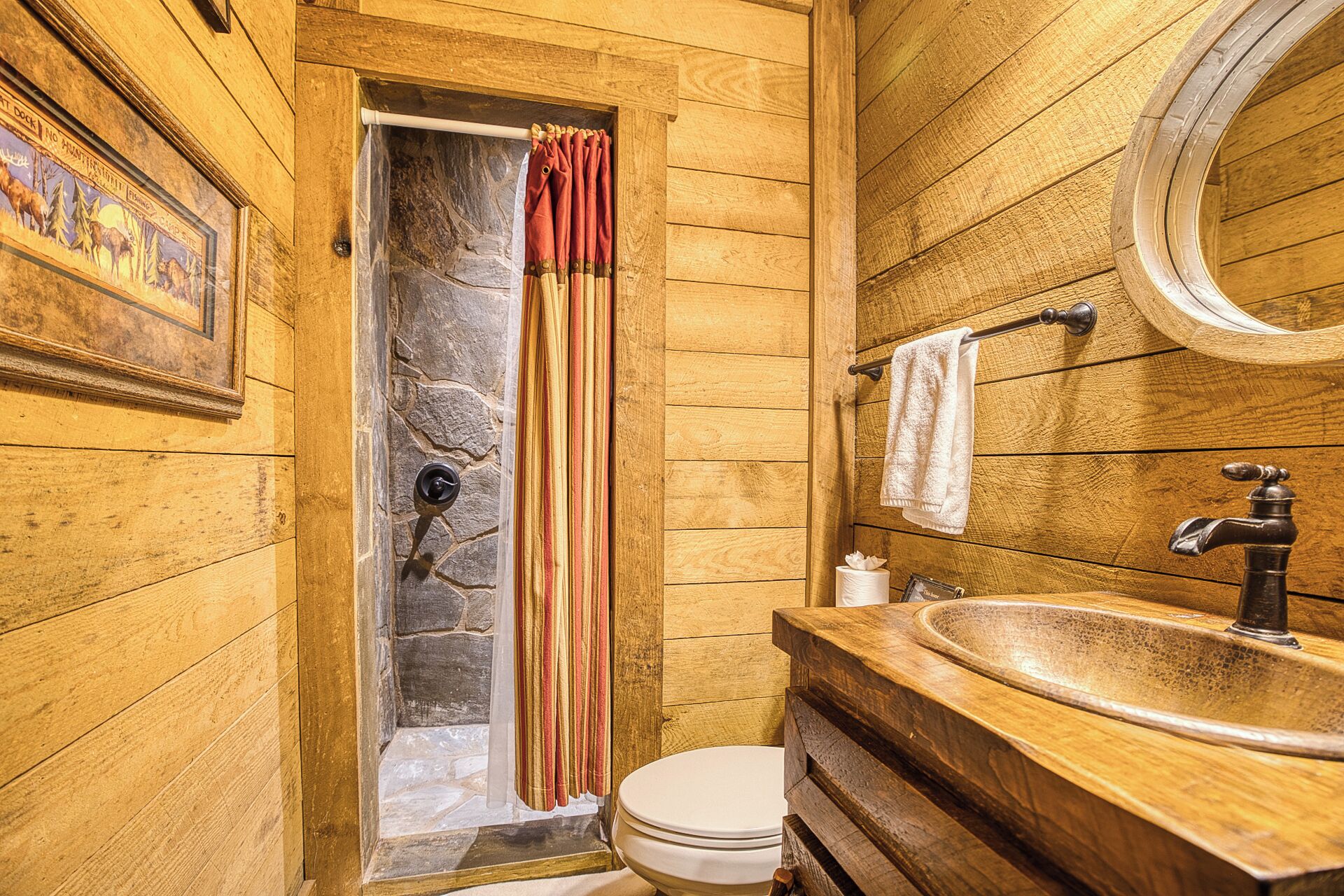 A wooden bathroom with a stone shower, a wooden sink, and a toilet.
