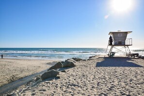 A lifeguard tower on a sandy beach with the ocean in the background.