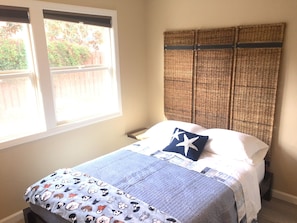 A bedroom with a bed, a window, and a headboard.