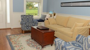 Una sala de estar con un sofá color crema, sillones estampados, una mesa de centro de madera y una alfombra floral.