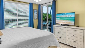 A hotel room with a bed, a television displaying 'Legacy Vacations', a window with blinds, and a view of the outdoors.