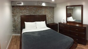 A bedroom with a brick wall, a wooden bed, a dresser, and a mirror. - Up to 50% off select nights! Huge Loft, Foosball Table, Professionally Cleaned!! (Nashville)