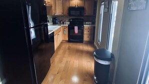 A kitchen with wooden cabinets, a black refrigerator, a microwave, and a stove. - Up to 50% off select nights! Huge Loft, Foosball Table, Professionally Cleaned!! (Nashville)