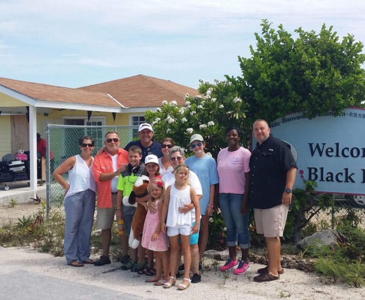 Un grupo de personas de pie frente a un cartel que dice "Welcome to Black Point".
