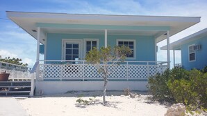 A two-story building with a blue and white exterior, a covered porch, and a small tree in front. - Seashell Cottage with breathtaking views! Near Swimming Pigs.  (exuma)