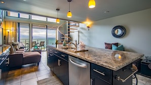 A modern kitchen with a central island, built-in appliances, and a view to the outside.
