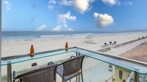 A glass table with chairs overlooking a beach.