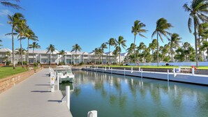 A marina with boats docked, a walkway, and a row of buildings with balconies. - Waterfront luxury Villa (29) with sunset views and boat slip (Marathon)
