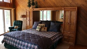 Quarto com uma cama grande, uma cadeira e um guarda-roupa.