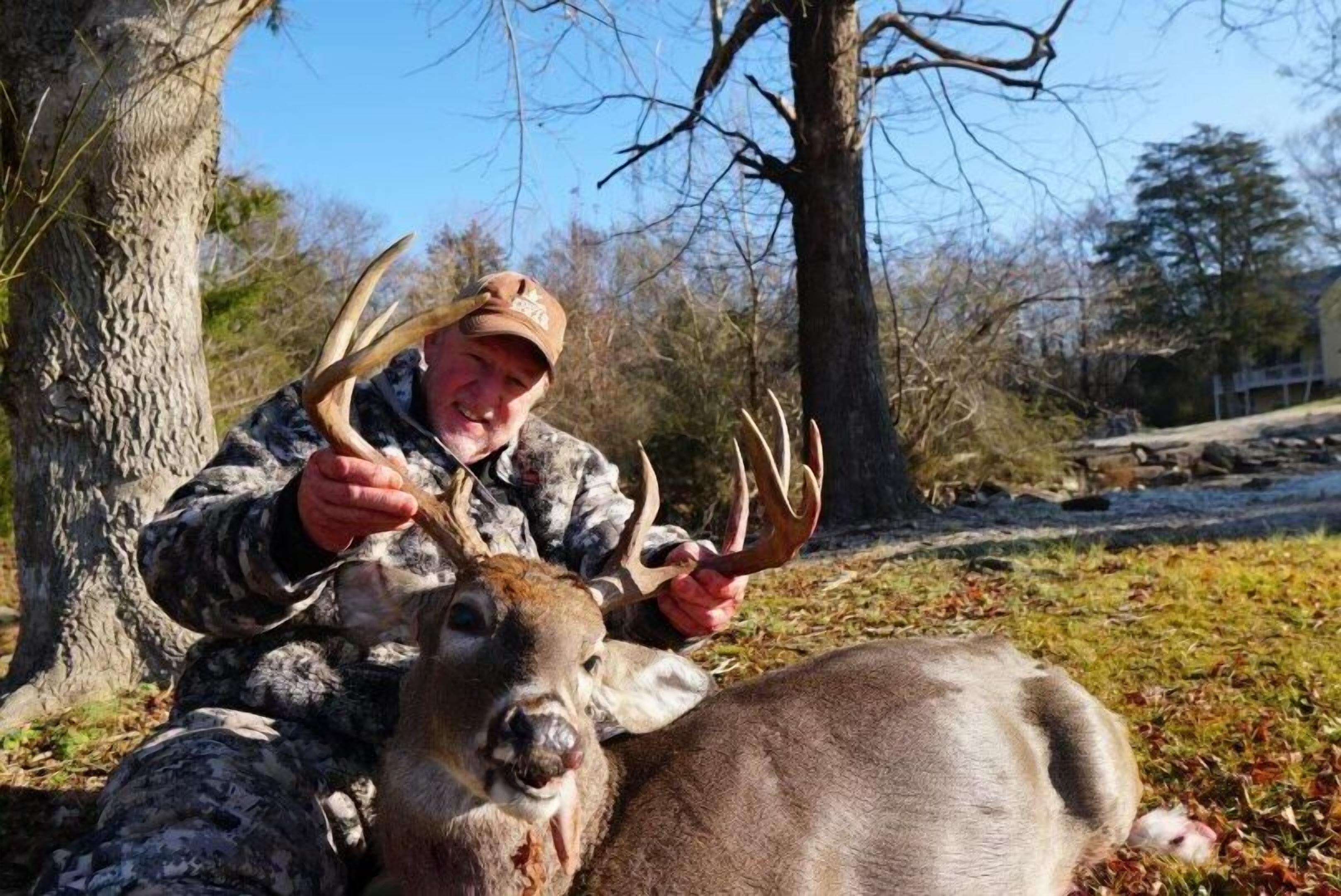 A person in camouflage attire holding deer antlers.