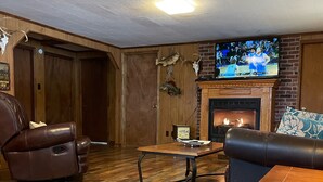 A living room with a fireplace, leather recliner, and a television. - Beautiful Rustic Cabin On Lincoln Lake Is A Sportsman paradise.   (Kelso)