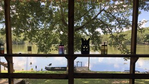 A wooden deck with a view of a lake, a boat, and a bag of dog food. - Beautiful Rustic Cabin On Lincoln Lake Is A Sportsman paradise.   (Kelso)