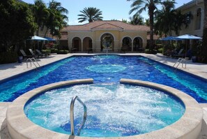 A swimming pool with a hot tub in the center, surrounded by lounge chairs and umbrellas. - Villa Renaissance 201: Book August Now And Save 10%! (Providenciales)