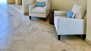 A lobby with two armchairs, a round side table, and a large abstract painting. - Villa Renaissance 201: Book August Now And Save 10%! (Providenciales)