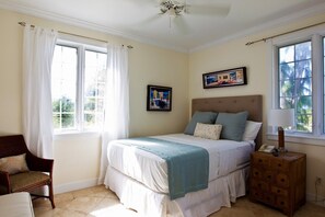 A bedroom with a bed, a chair, a nightstand, and a window with curtains. - Villa Renaissance 201: Book August Now And Save 10%! (Providenciales)