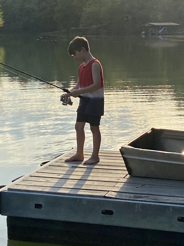 A person standing on a wooden dock holding a fishing rod.