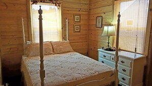 Un letto a baldacchino con copripiumino floreale, un comodino con lampada e una cassettiera.