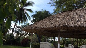 A covered outdoor seating area with wicker furniture and a thatched roof. - Golf (in Front Tee 11), Pool, Service, One Story, 4 Rooms, Internet, Palapa, Van (Ixtapa, Zihuatanejo)