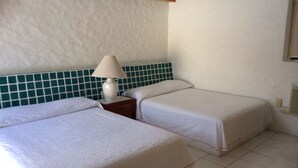 A hotel room with two beds, a nightstand with a lamp, and a tiled wall. - Golf (in Front Tee 11), Pool, Service, One Story, 4 Rooms, Internet, Palapa, Van (Ixtapa, Zihuatanejo)