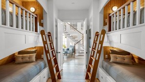 A narrow hallway with a staircase leading to a second floor. There are two seating areas on either side of the hallway, each with a bench and pillows. - PRIVATE BEACH ACCESS-Newly Refurbished-Pool-4 Bikes-Close to Town Center/Beach (Panama City Beach)