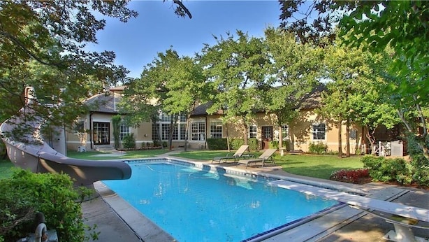 A swimming pool surrounded by trees and a house with a covered patio. - Spacious, newly remodeled home near I-35 in Edmond (Edmond)