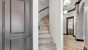 A hallway with a wooden staircase, a door, and a light fixture. - Spacious, newly remodeled home near I-35 in Edmond (Edmond)