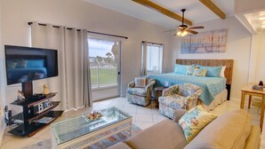 A spacious bedroom with a large bed, a television, and a balcony with curtains. - El Matador 627 - FREE TICKETS!! Your stay includes free tickets to many area attractions! (Fort Walton Beach)