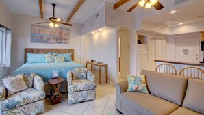 A bedroom with a bed, two chairs, a sofa, a ceiling fan, and a kitchen area. - El Matador 627 - FREE TICKETS!! Your stay includes free tickets to many area attractions! (Fort Walton Beach)