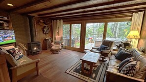 A cozy living room with a fireplace, comfortable seating, and a television. - Spa Cabin: Lakefront w Private Sauna & Hot Tub, Kayaks, Dock, 5 Star Clean Rated (Oakland)