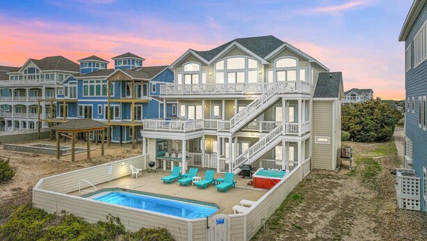 A beachfront property with a large pool, multiple balconies, and a covered patio area. - Luxurious Oceanfront Home with Private Pool, Hot Tub, Elevator, Tiki Bar (Avon)