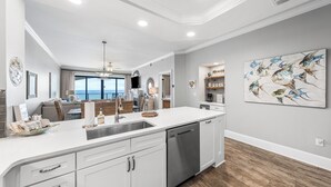 Una cucina moderna con lavastoviglie, una grande isola con lavello e zona pranzo con vista.