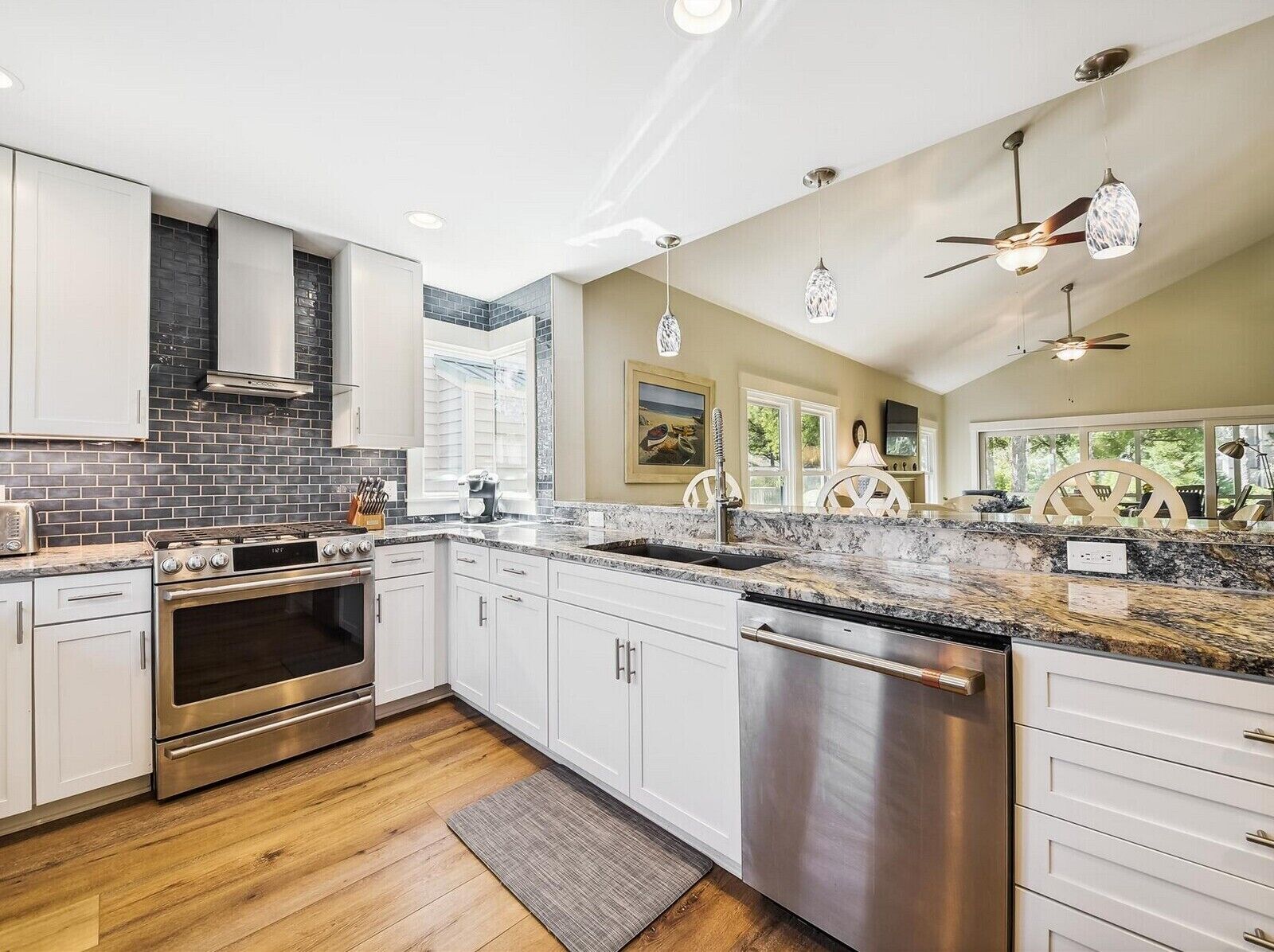 A modern kitchen with white cabinets, a stainless steel stove, and a dishwasher.