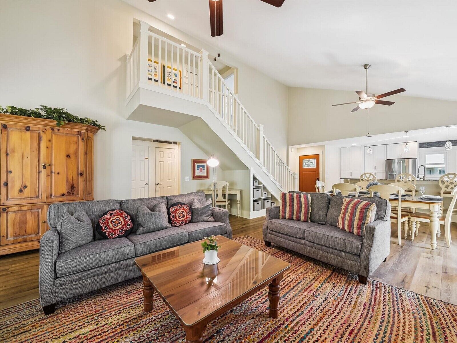 A spacious living area with two grey sofas, a wooden coffee table, and a staircase leading to an upper level.
