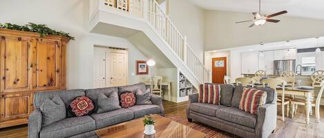 A spacious living area with two grey sofas, a wooden coffee table, and a staircase leading to an upper level.