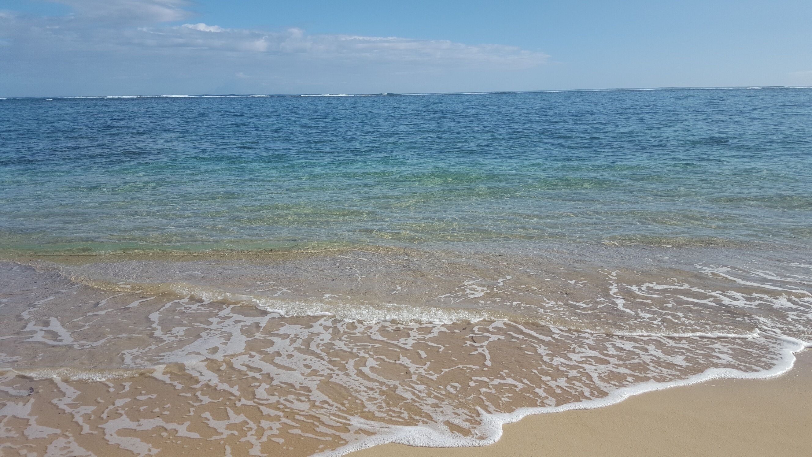 Una playa con agua cristalina y olas suaves.