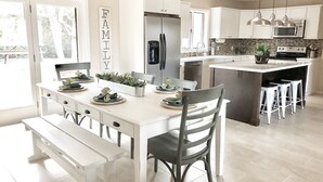 Une cuisine moderne avec des meubles blancs, un îlot central et un coin repas équipé d’une banquette.