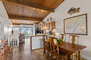 A spacious kitchen with wooden cabinets, a dining area with a wooden table and chairs, and a large map on the wall.
