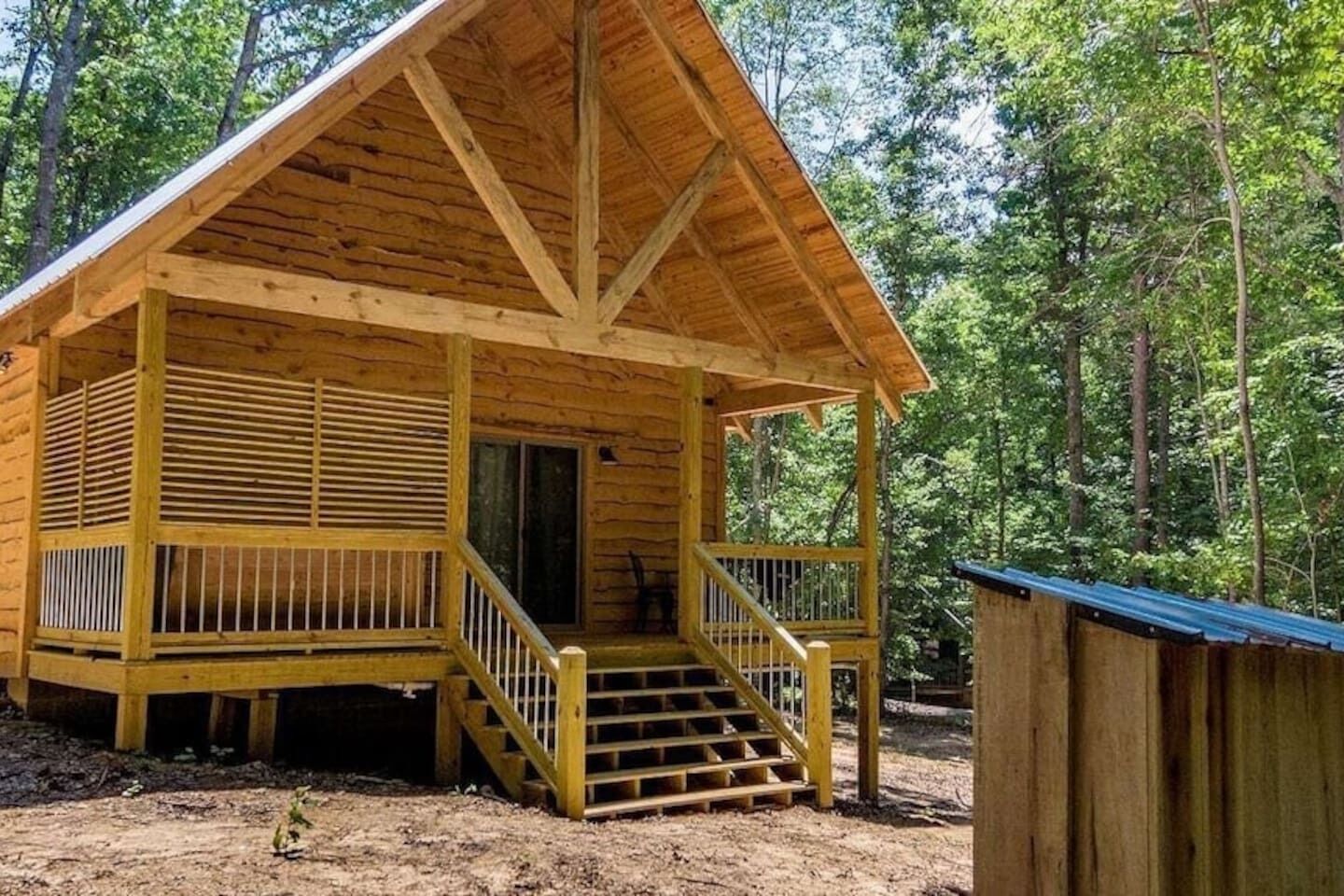 A wooden cabin with a porch and a staircase leading to the entrance.