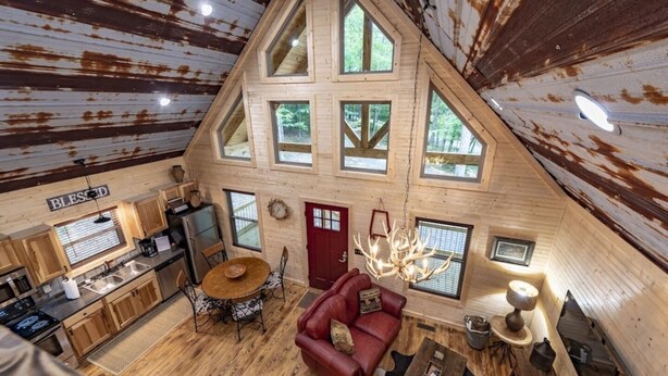 A rustic cabin interior with a kitchen, dining area, and living room. - Quail's Nest with Hot tub (Mentone)