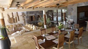 A spacious indoor area with a dining table set for four, surrounded by wooden chairs. There is a seating area with a sofa and cushions, and a stone wall in the background. - ...casaemelina-puertoescondido...contact us for a deal !
25m Pool, huge property (Puerto Escondido)