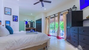 Una habitació d'hotel amb llit, armari, ventilador de sostre i finestra amb cortines.
